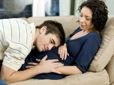 Man listening to his pregnant wife' stomach