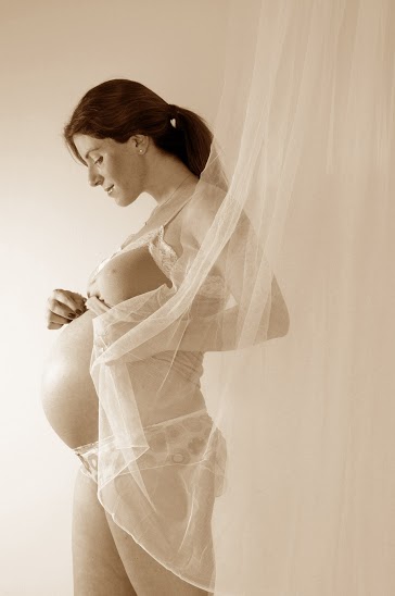 אישה בהריון מתקדם עם בטן חשופה מחייכת