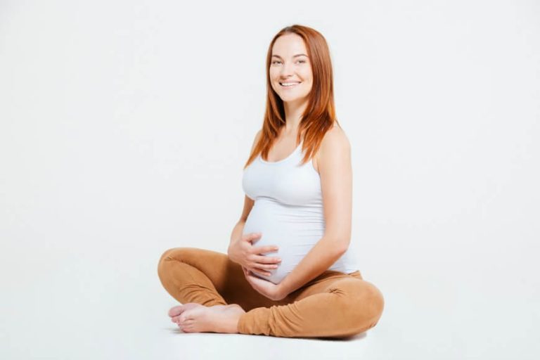 Happy pregnant woman sitting on the floor