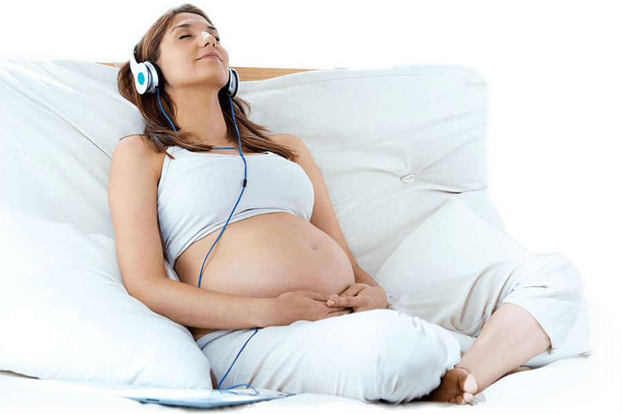 אשה בהריון יושבת על הספה ומאזינה למוסיקה באזניות