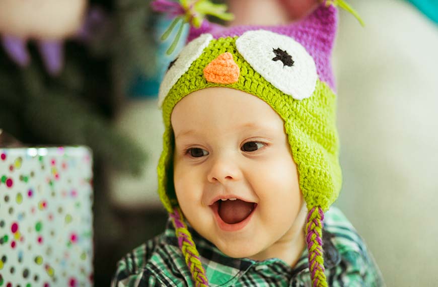 תינוק צוחק עם כובע ינשוף צבעוני