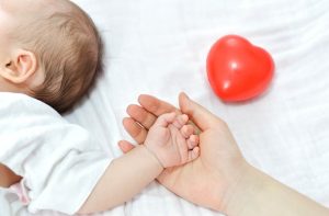 יד של תינוק על יד של אמא ולב אדום ליד