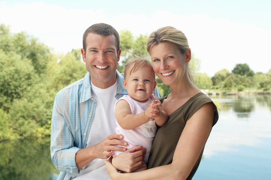 Couple with child standing by lake half length