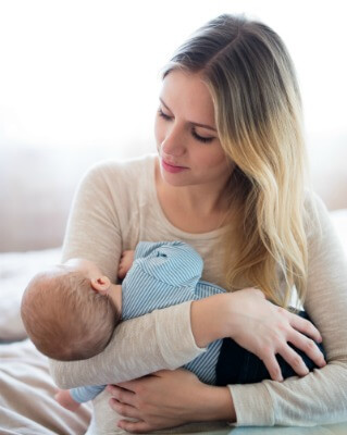 beautiful-young-mother-holding-her-baby-son-in-her-arms-sitting-on-bed
