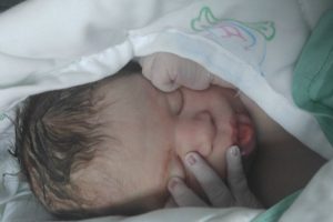 newborn baby with hands on his face