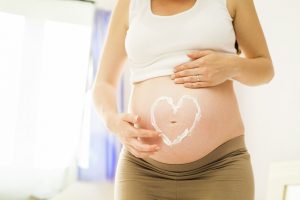 אשה בהריון עם איור לב על הבטן